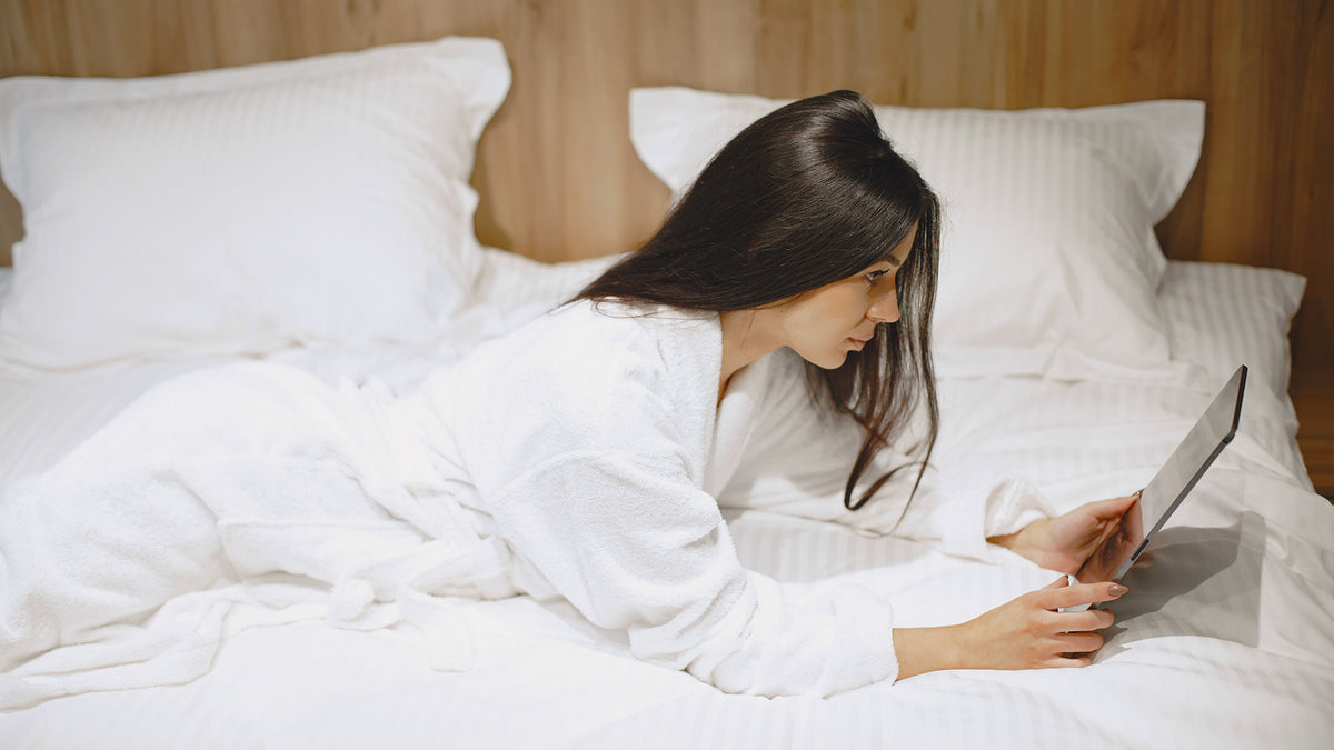A hand is placed on a soft white bed